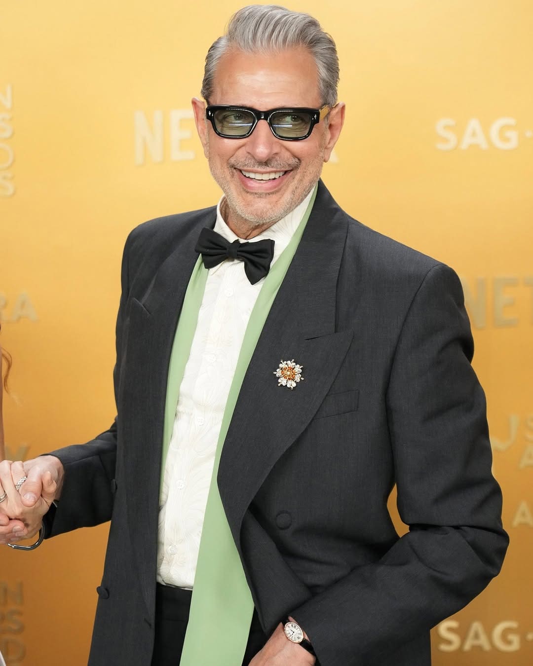 Jeff Goldblum in Prada suit and Tiffany & Co. watch and brooch